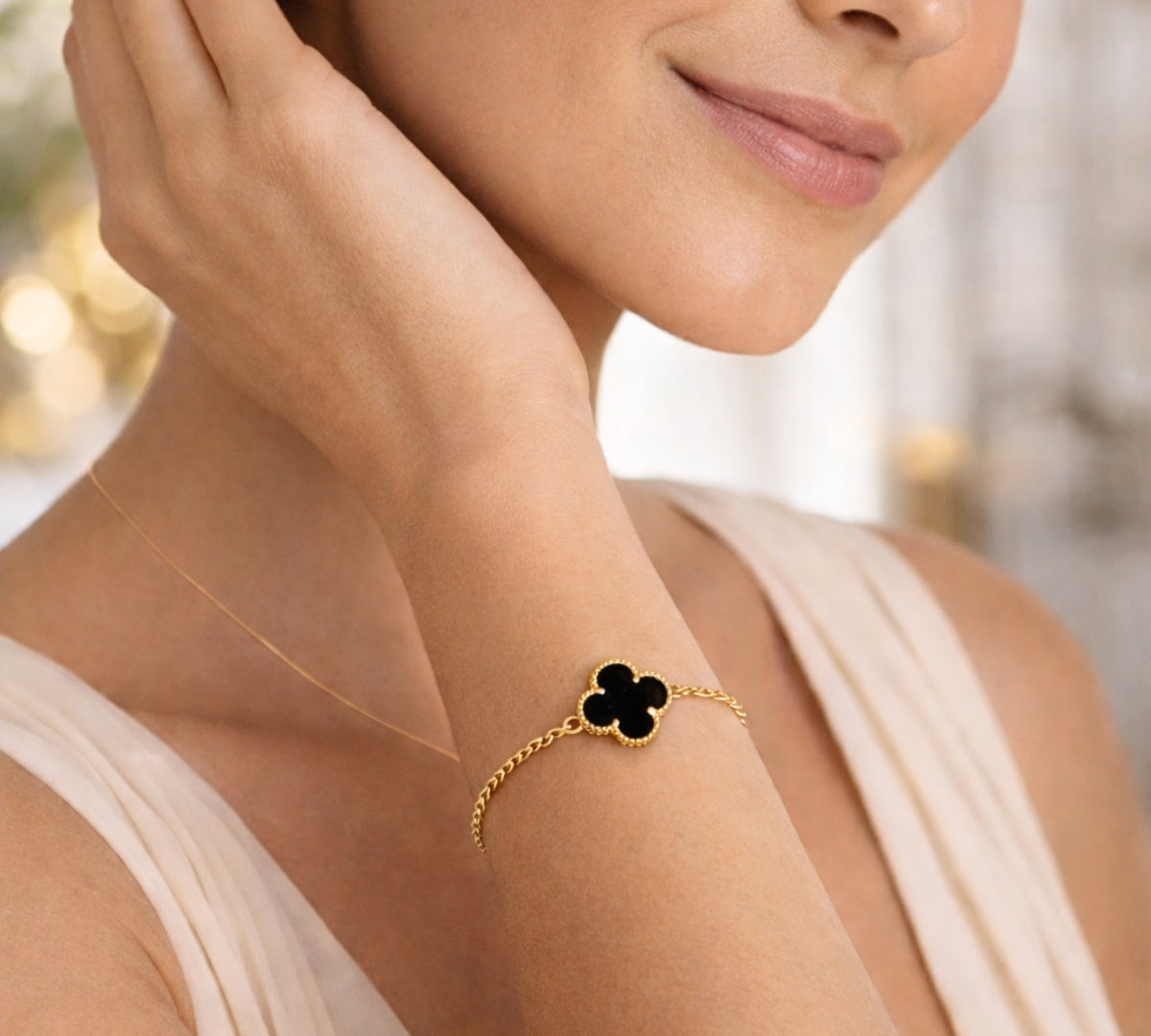Detalle de modelo luciendo la pulsera Flor VC en la muñeca, resaltando el brillo del oro laminado y el contraste del color  negro.