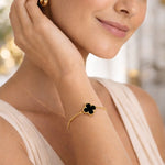 Detalle de modelo luciendo la pulsera Flor VC en la muñeca, resaltando el brillo del oro laminado y el contraste del color  negro.