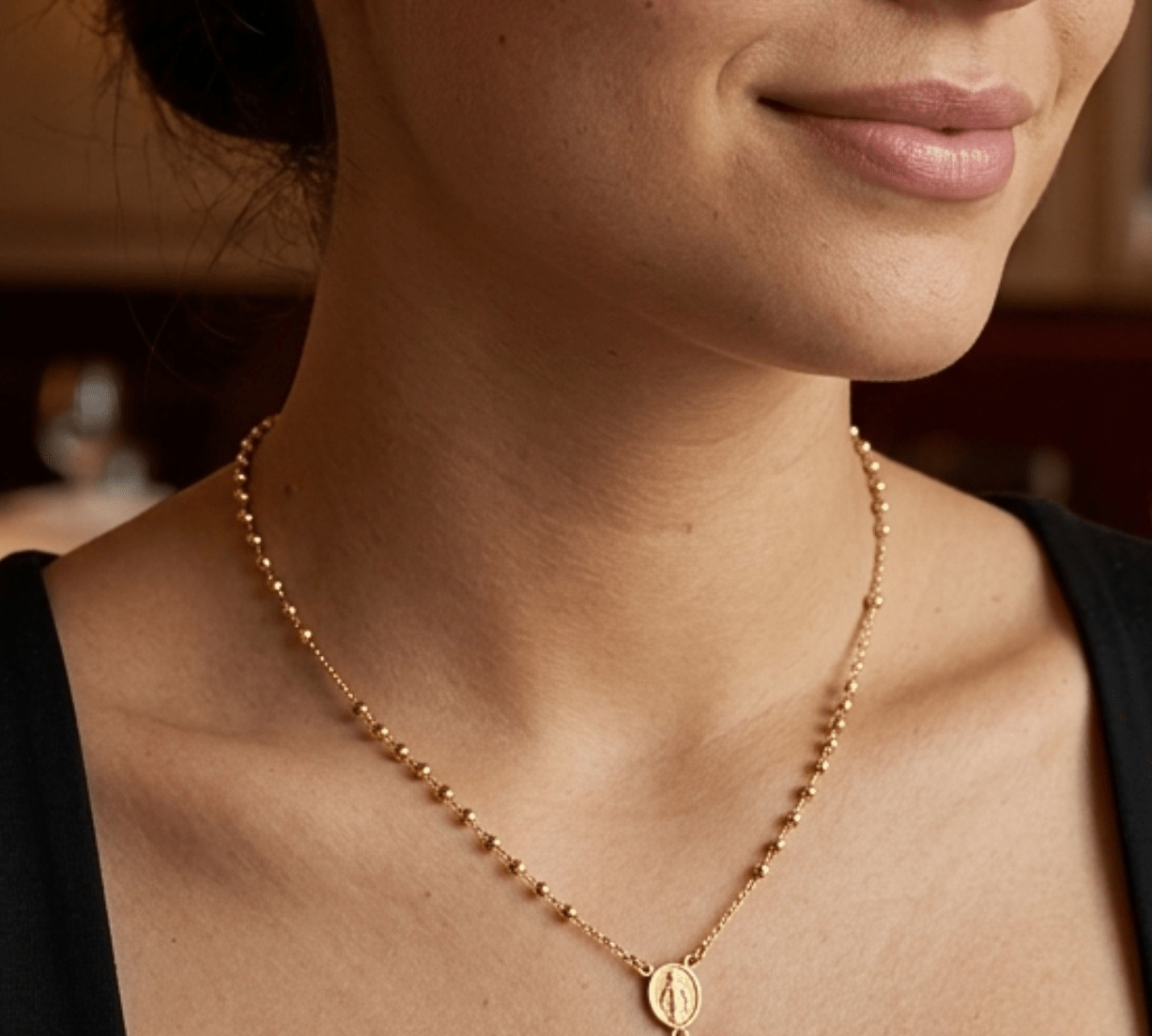 modelo con Collar tipo rosario de plata de ley 925 enchapada en oro 18k con pequeñas esferas, medalla central y dije de cruz colgante.