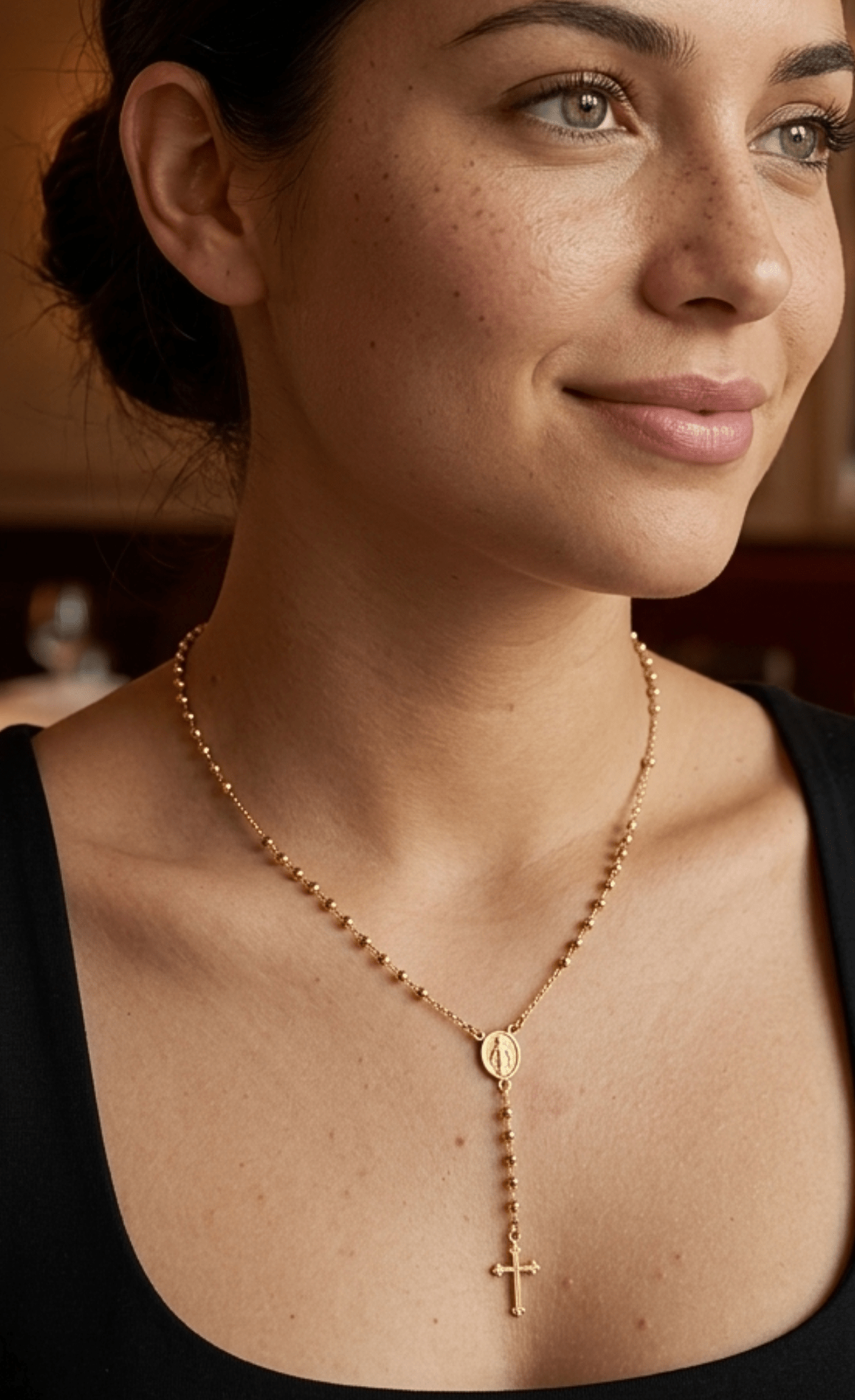 modelo con Collar tipo rosario de plata de ley 925 enchapada en oro 18k con pequeñas esferas, medalla central y dije de cruz colgante.