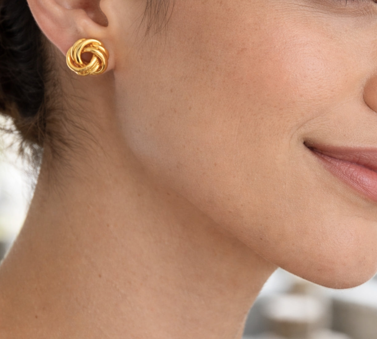 modelo con Aretes tipo topo de plata de ley 925 con enchape de oro 18k en diseño de nudo texturado