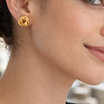 modelo con Aretes tipo topo de plata de ley 925 con enchape de oro 18k en diseño de nudo texturado