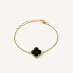 Pulsera de oro laminado con dijes de flor de cuatro pétalos texturizados y centros de color negro brillante.