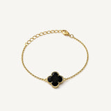 Pulsera de oro laminado con dijes de flor de cuatro pétalos texturizados y centros de color negro brillante.