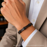 modelo con pulsera de cuero marrón para hombre con tres separadores negros de acero y broche magnético rectangular.