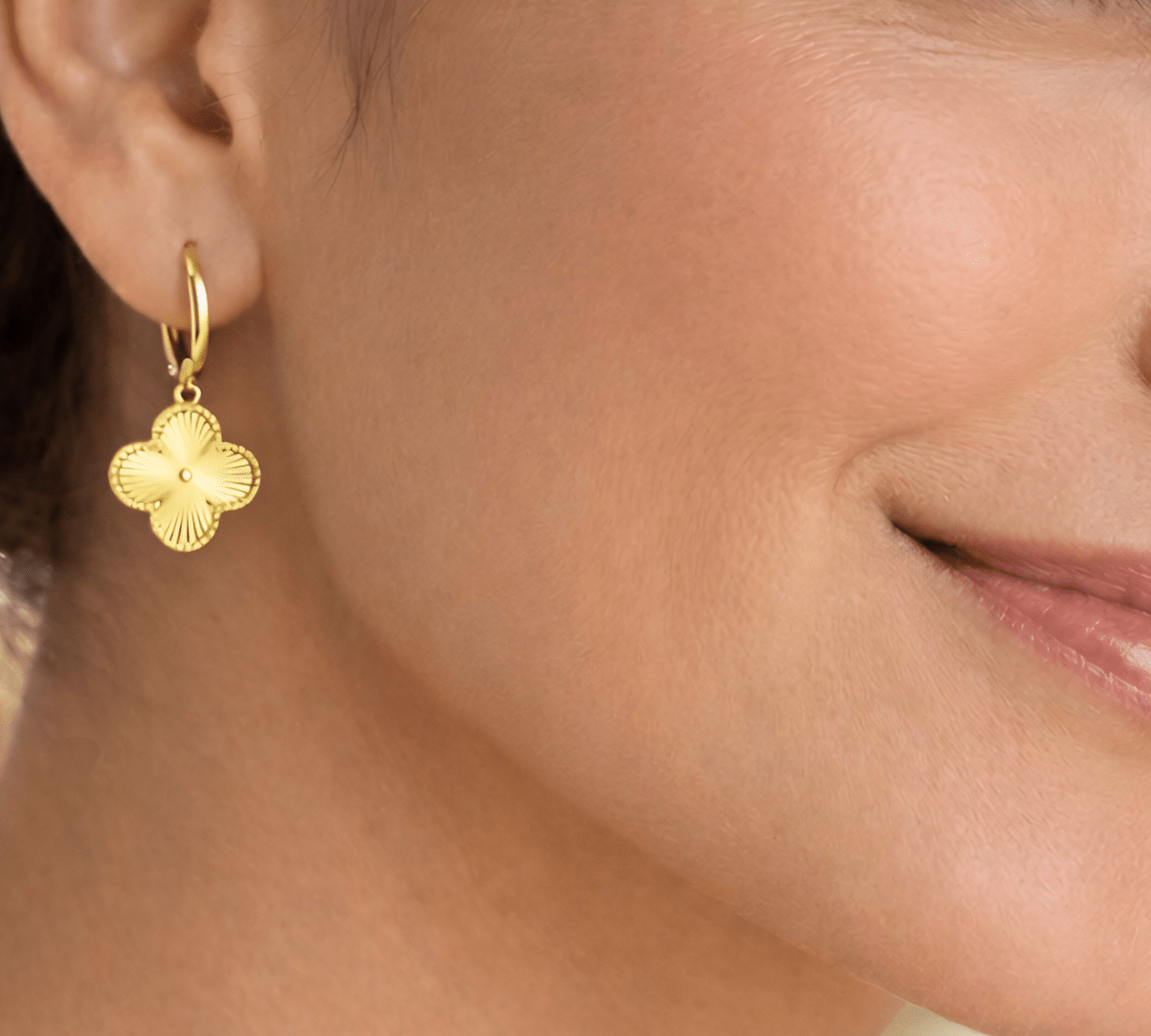 Detalle de modelo luciendo los aretes Flor VC, resaltando el brillo y el relieve del dije floral.