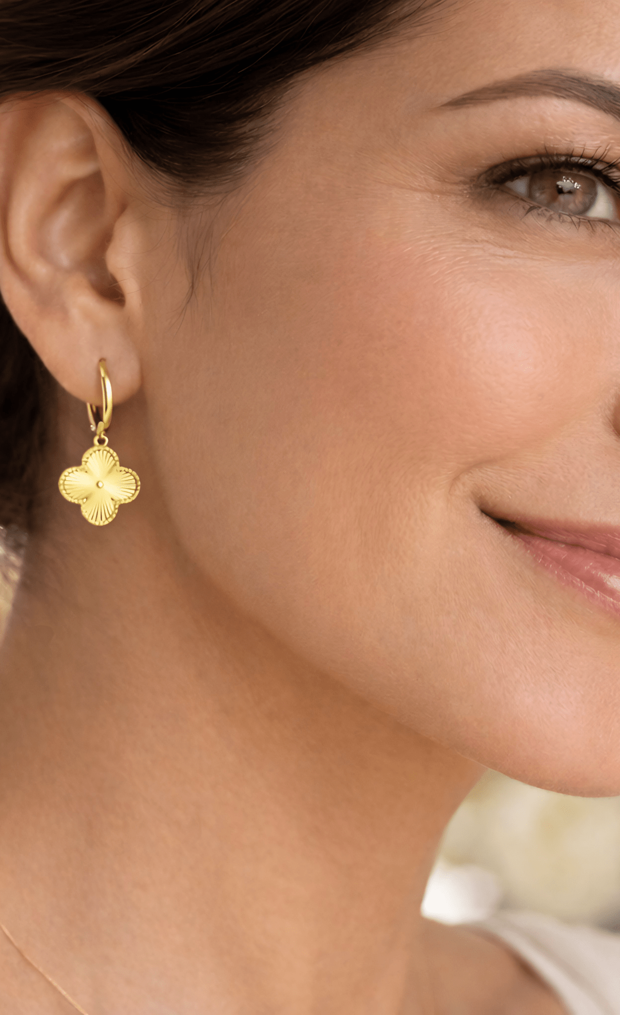 Detalle de modelo luciendo los aretes Flor VC, resaltando el brillo y el relieve del dije floral.