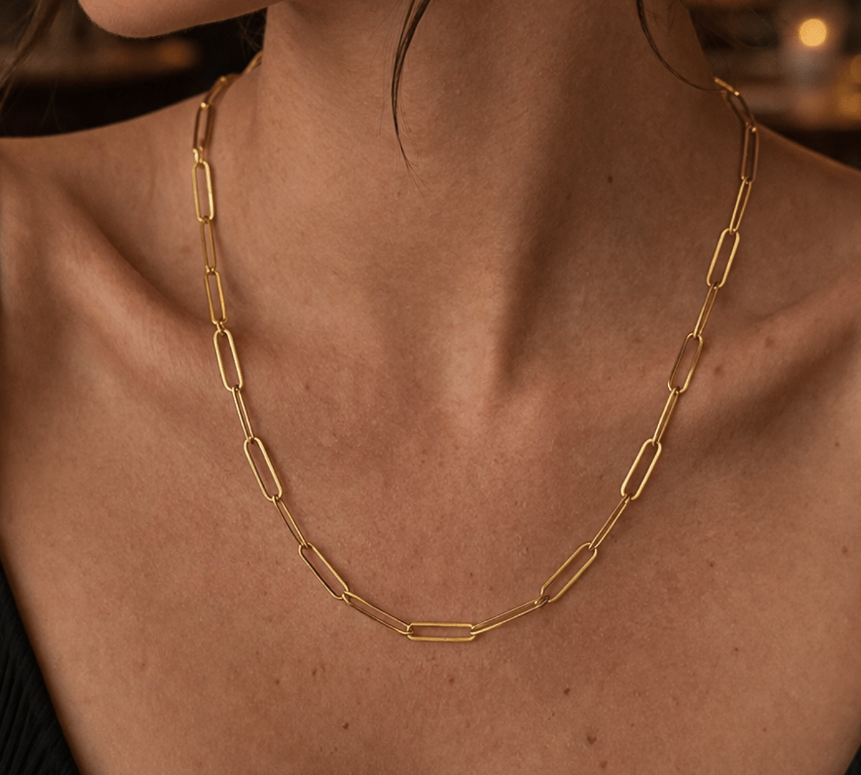 Modelo luciendo el collar de cadena clip plano de plata enchapada en oro 18k, resaltando un estilo sofisticado y moderno.