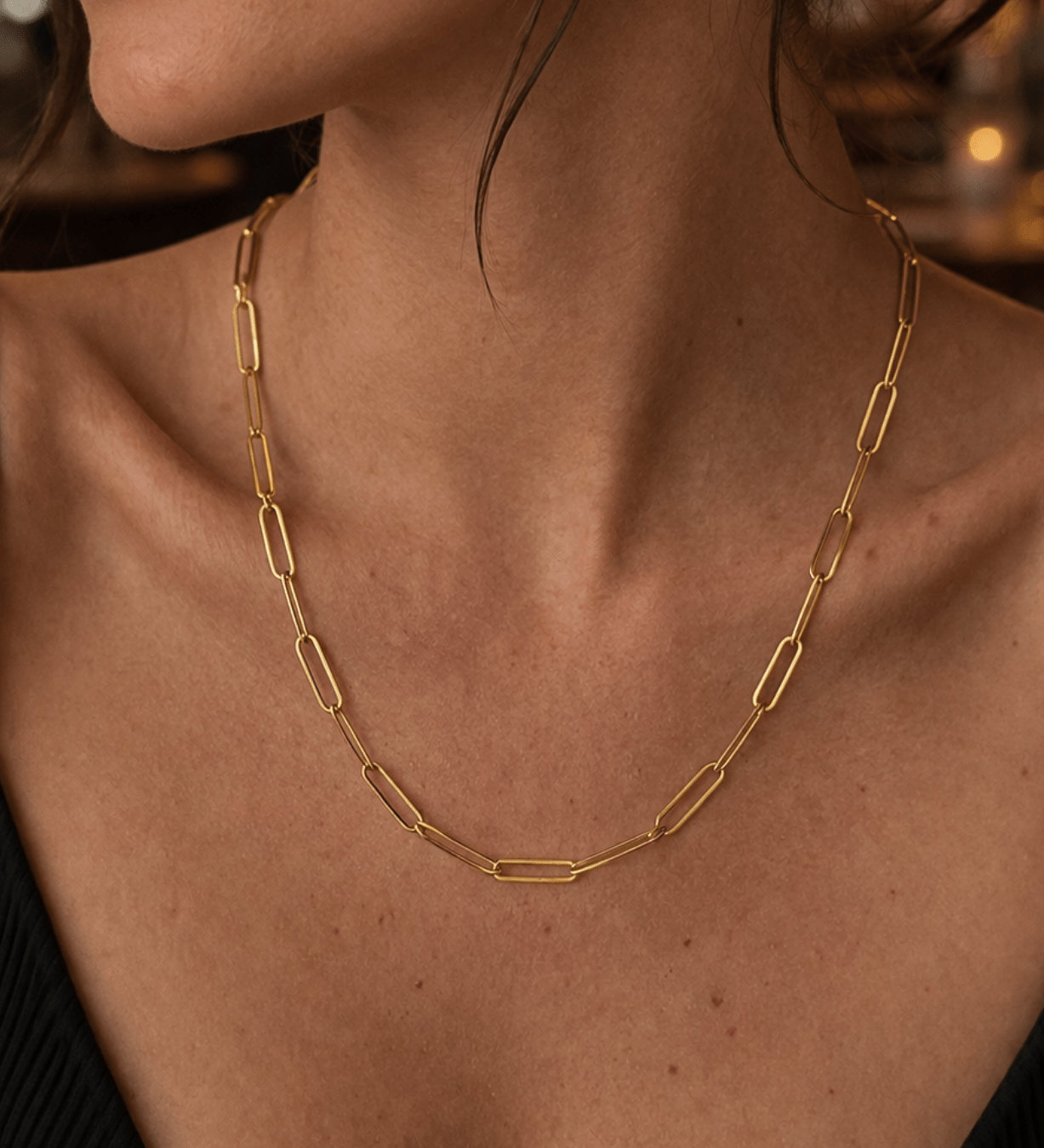 Modelo luciendo el collar de cadena clip plano de plata enchapada en oro 18k, resaltando un estilo sofisticado y moderno.