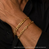 Pulsera masculina de oro laminado con eslabones planos tipo Grumet lucida en la muñeca de un caballero sobre una camisa negra.
