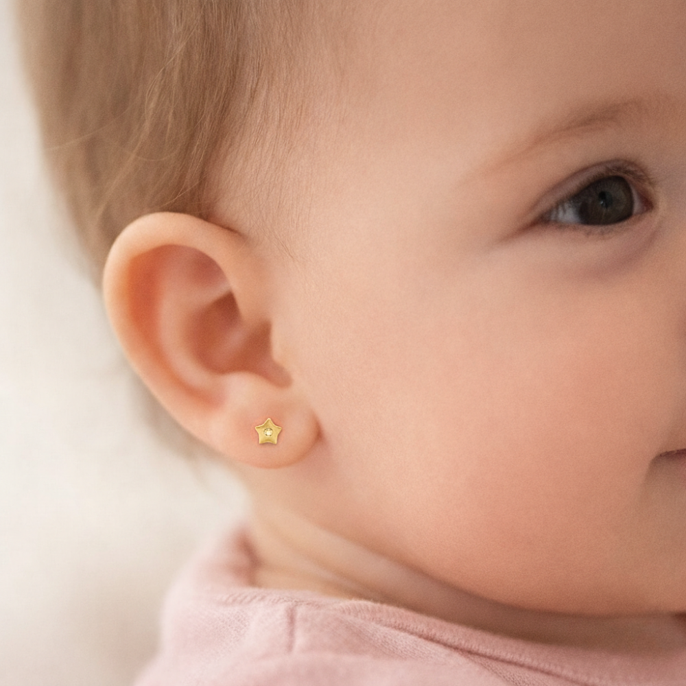 Bebé usando arete de estrella elaborado en oro 18K, diseño delicado y seguro para recién nacidas.
