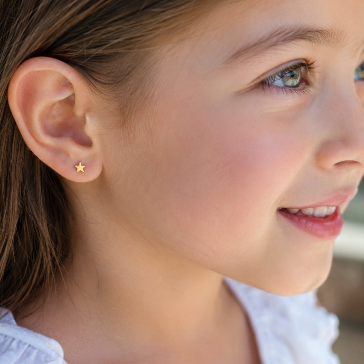 niña con aretes de estrellita de oro laminado, ideal para uso diario.