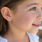 niña con aretes de estrellita de oro laminado, ideal para uso diario.