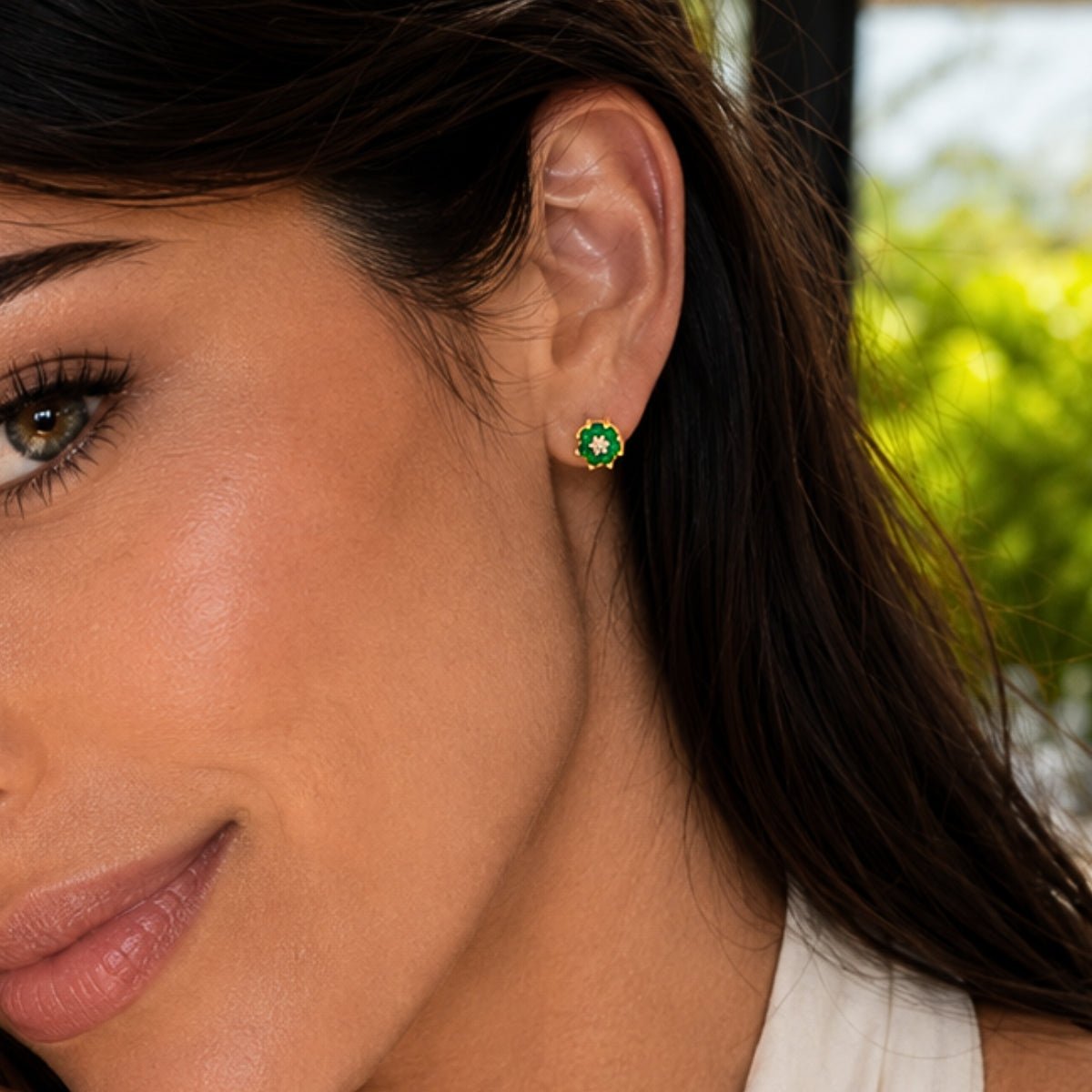 close up de modelo luciendo arete roseta verde esmeralda con cristales y oro laminado de ambar joyería