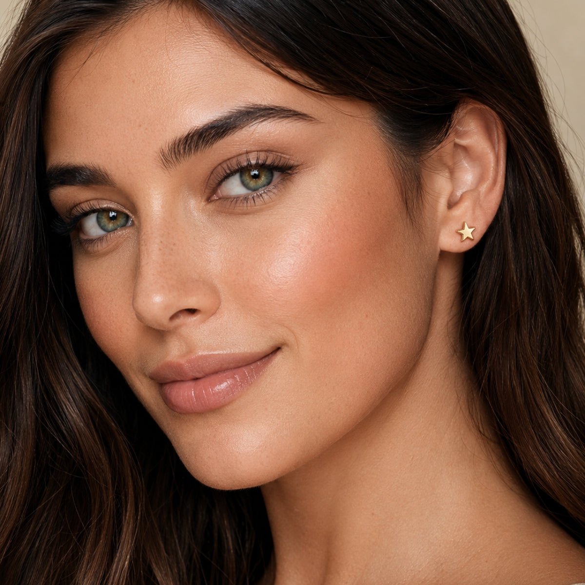 modelo luciendo Arete estrella enchapado en oro 18k y poste de acero para joyería de AMBAR joyería fina