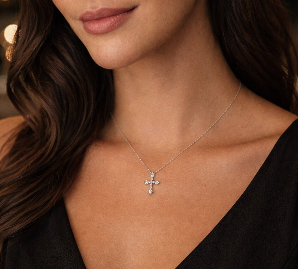 Modelo con collar con dije de cruz de plata 925 enchapada en rodio y circonitas brillantes.