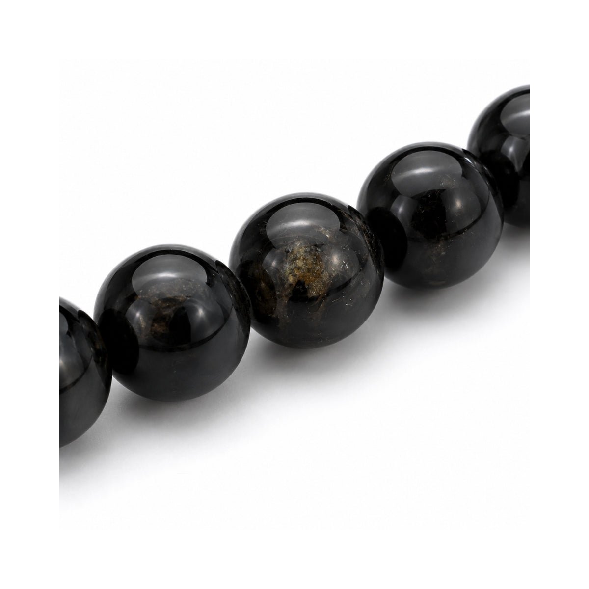 Primer plano de las esferas pulidas de piedra natural turmalina negra con detalles de brillo natural de la pulsera elástica Orión.