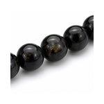 Primer plano de las esferas pulidas de piedra natural turmalina negra con detalles de brillo natural de la pulsera elástica Orión.