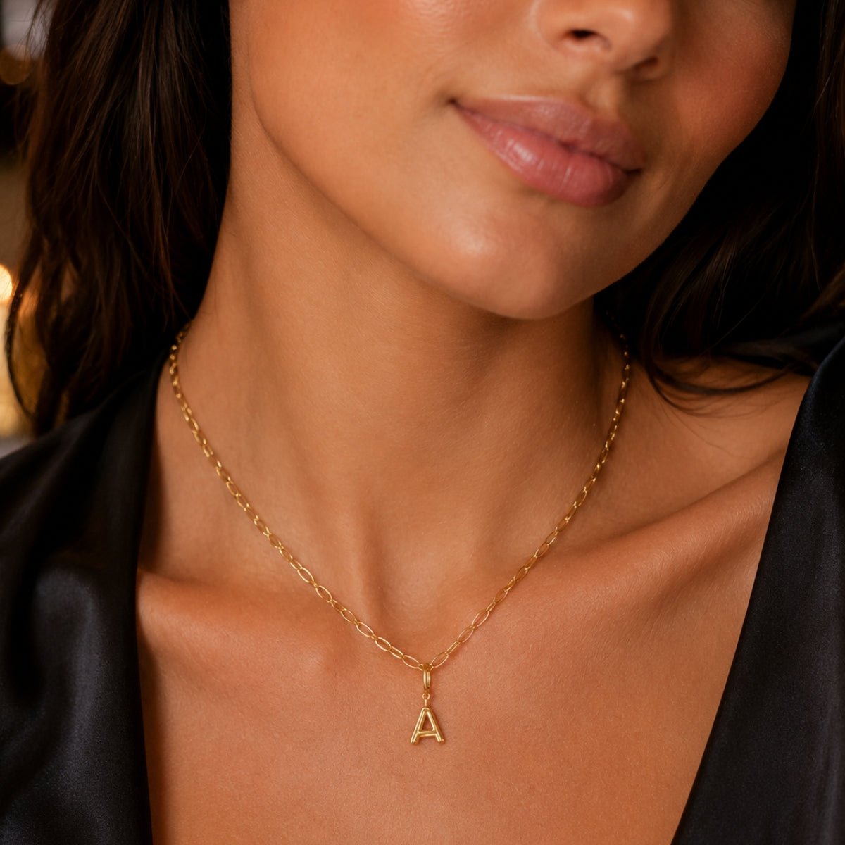 modelo luciendo  un dije Inicial letra a con broche bisagra enchapado en oro 18k de AMBAR joyeria fina
