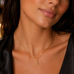 modelo luciendo  un dije Inicial letra a con broche bisagra enchapado en oro 18k de AMBAR joyeria fina