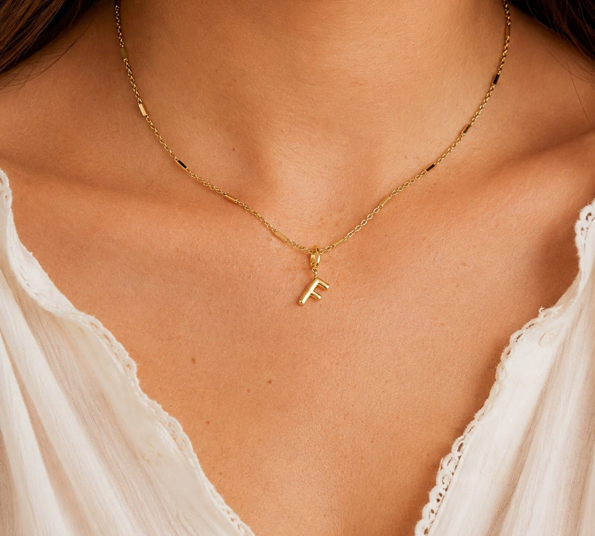 modelo luciendo un Dije Inicial letra F con broche bisagra enchapado en oro 18k de AMBAR joyeria fina