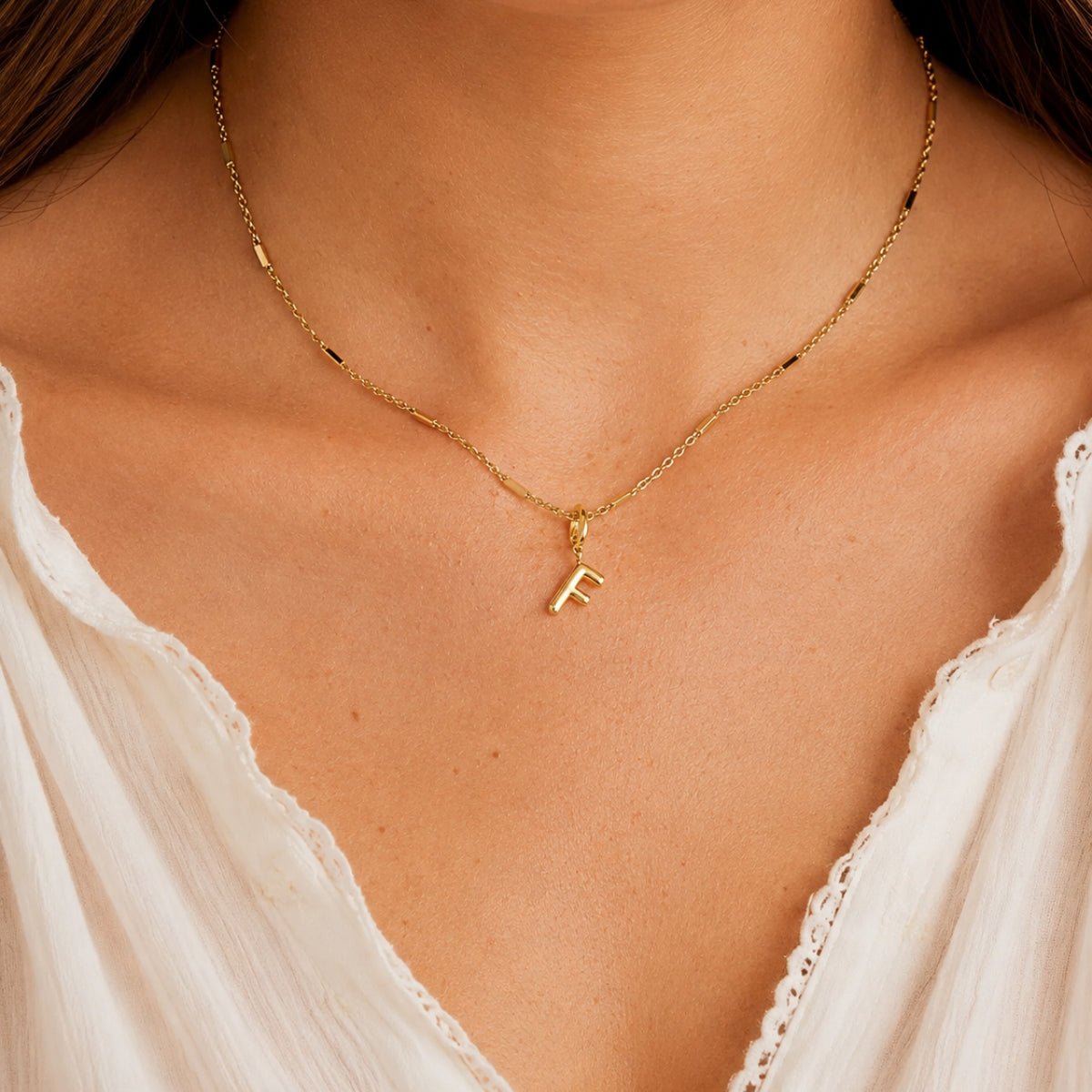 modelo luciendo un Dije Inicial letra F con broche bisagra enchapado en oro 18k de AMBAR joyeria fina