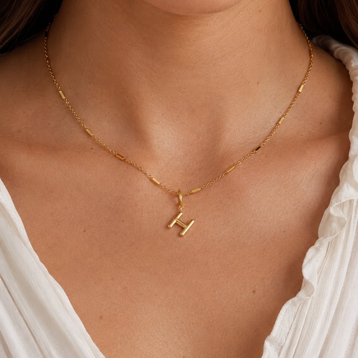 modelo luciendo Dije Inicial letra H con broche bisagra enchapado en oro 18k de AMBAR joyeria fina