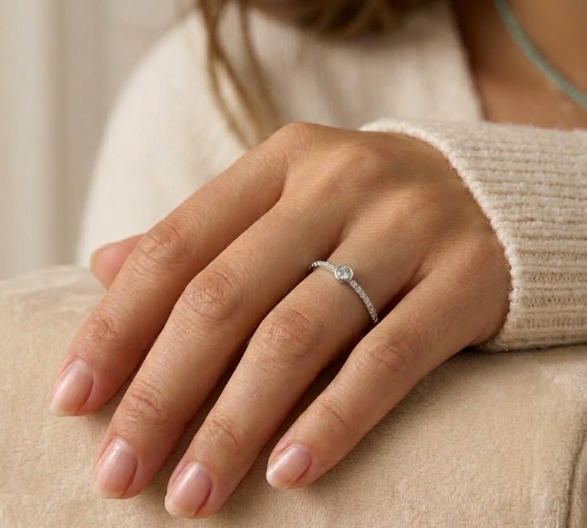 Detalle de mano luciendo anillo fino semi rivier de plata 925; joyería elegante y minimalista.