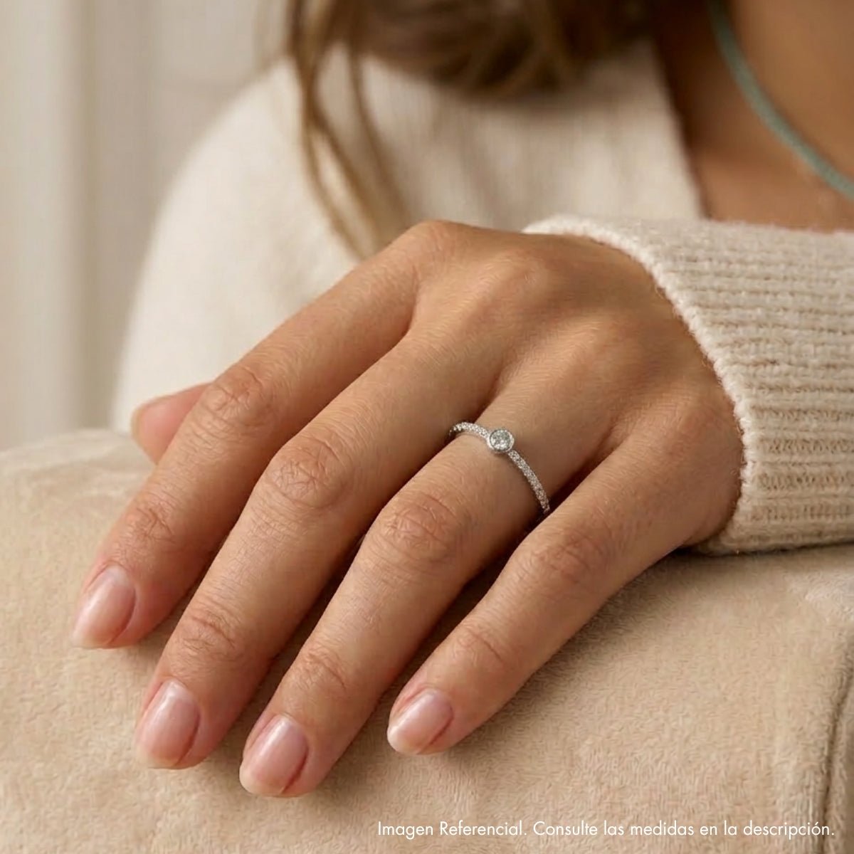 Detalle de mano luciendo anillo fino semi rivier de plata 925; joyería elegante y minimalista.