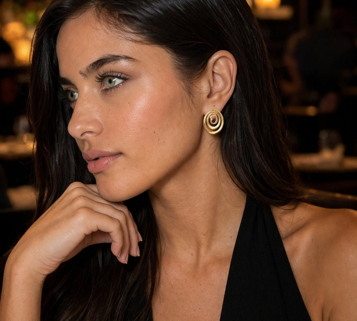 modelo con Aretes ovalados en oro laminado con diseño espiral y brillo tipo oro, estilo elegante.