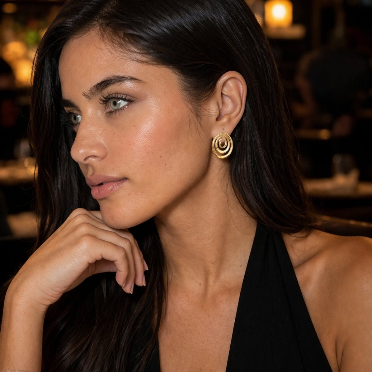 modelo con Aretes ovalados en oro laminado con diseño espiral y brillo tipo oro, estilo elegante.