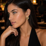 modelo con Aretes ovalados en oro laminado con diseño espiral y brillo tipo oro, estilo elegante.