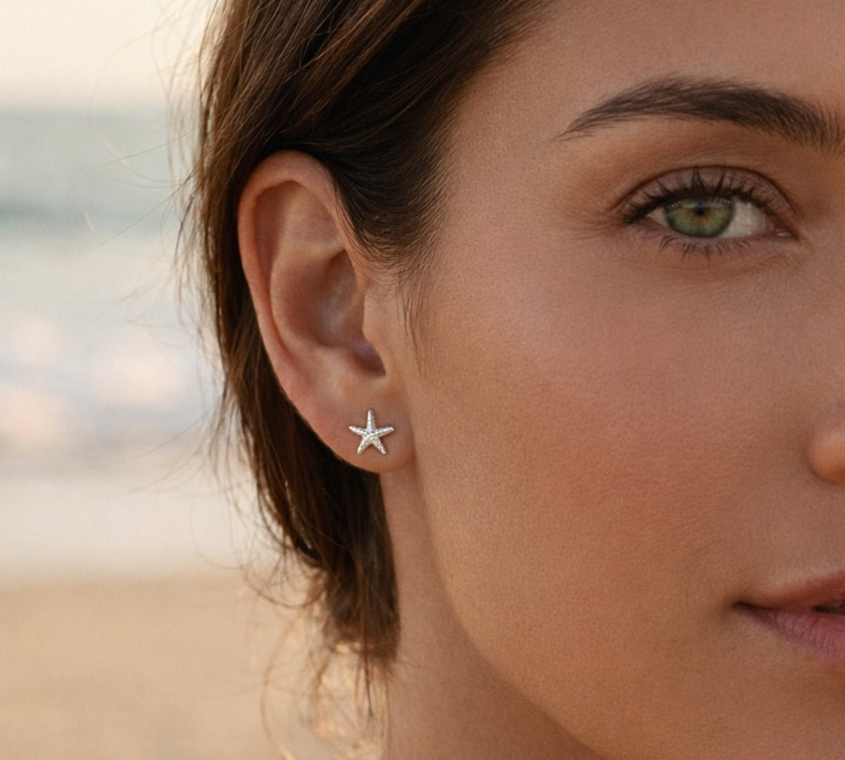 Detalle de oreja con aretes tiny de estrella de mar en plata 925; tendencia de piercings múltiples.