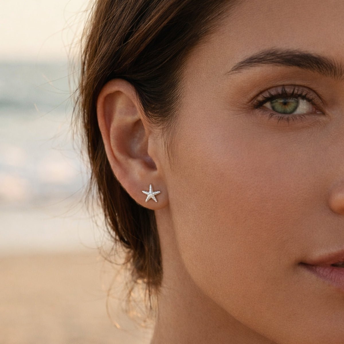 Detalle de oreja con aretes tiny de estrella de mar en plata 925; tendencia de piercings múltiples.
