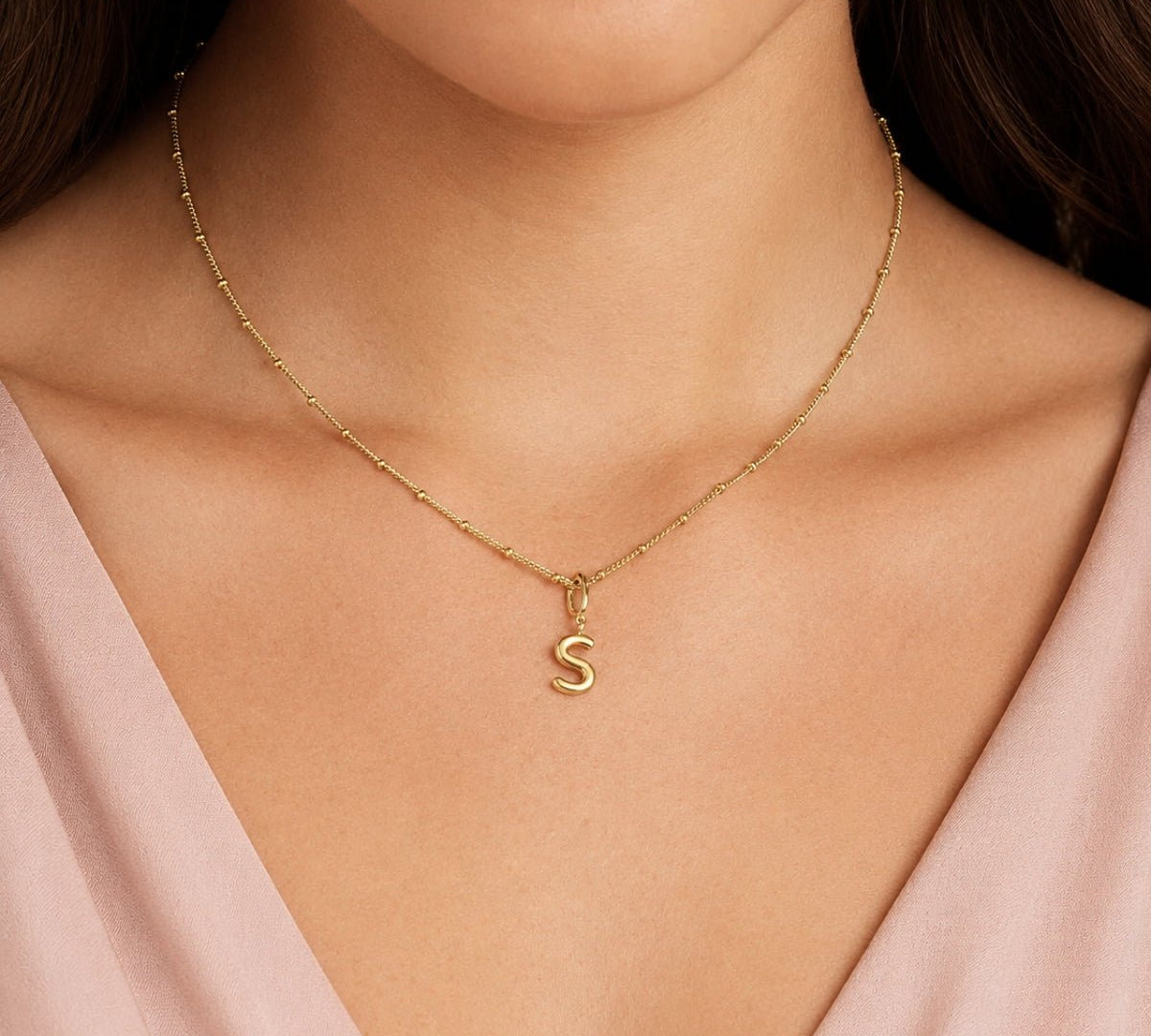 modelo luciendo un dije Inicial letra s con broche bisagra enchapado en oro 18k de AMBAR joyería fina.