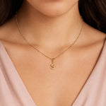 modelo luciendo un dije Inicial letra s con broche bisagra enchapado en oro 18k de AMBAR joyería fina.