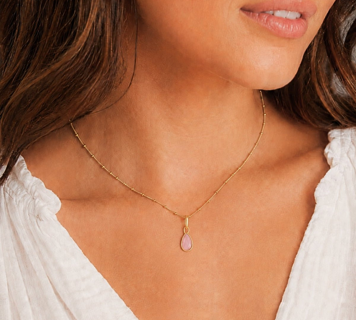 Modelo luciendo un dije Power Gemstone love cuarzo rosa enchapado en oro 18K de AMBAR Joyería Fina