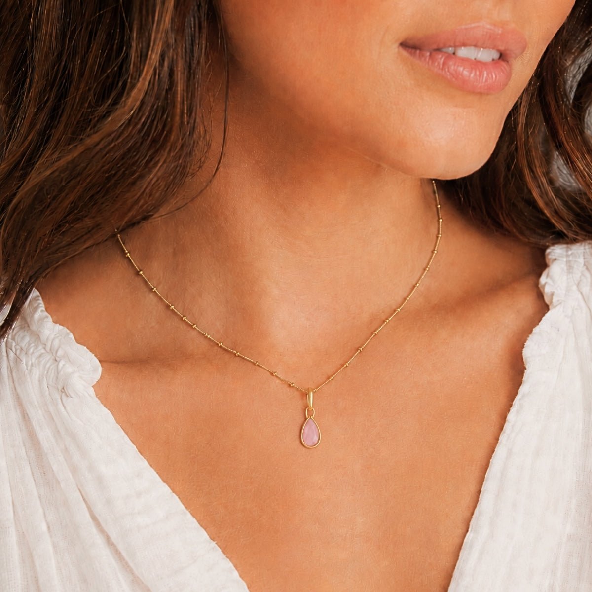 Modelo luciendo un dije Power Gemstone love cuarzo rosa enchapado en oro 18K de AMBAR Joyería Fina