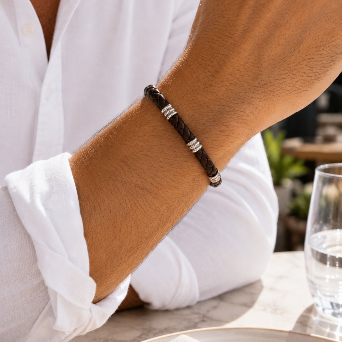 modelo con Pulsera Atlas de cuero trenzado marrón chocolate de 6 mm con broche magnético y detalles en acero inoxidable.