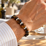 modelo con pulsera Hermes Regulable para hombre con Ojo de tigre de 8 mm y 10mm, aplicaciones de Plata 925 y tejido en macramé.