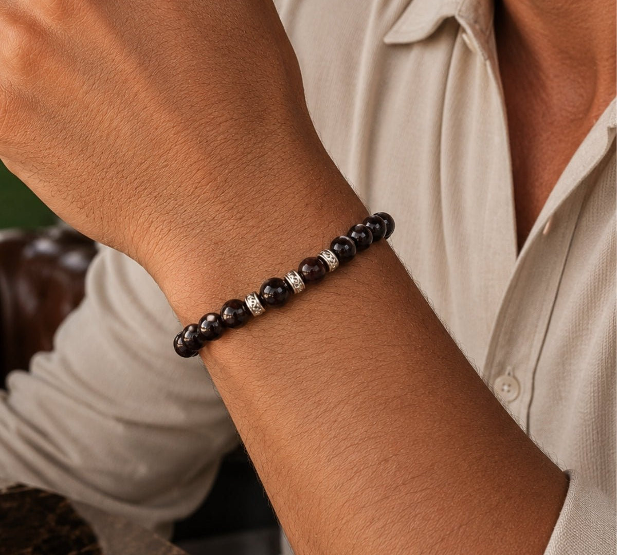 modelo con pulsera elástica para hombre modelo Hermes con hilo de silicona, esferas de rodonita borgoña y tres aros texturizados de plata 925.