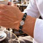 modelo con Pulsera San Benito Imperial Grand con piedras naturales de obsidiana de 10 mm, dije San Benito de acero inoxidable y donas de acero.