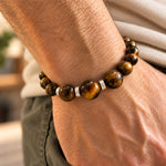 modelo con pulsera Hermes Regulable para hombre con Ojo de tigre de 8 mm y 10mm, aplicaciones de Plata 925 y tejido en macramé.