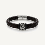 Pulsera Cuero Trenzado Vulcano de cuero negro con aplique central de acero inoxidable texturizado y bandas de silicona negra.