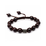 Pulsera tejida para hombre modelo Ares con hilo marrón, esferas de rodonita  y tres aros de plata 925 quemada sobre fondo blanco.