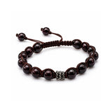 Pulsera tejida para hombre modelo Ares con hilo marrón, esferas de rodonita  y tres aros de plata 925 quemada sobre fondo blanco.